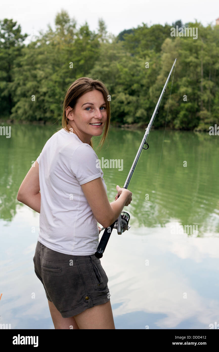 Brünette Frau Angeln an einem See mit grünem Wasser Stockfoto