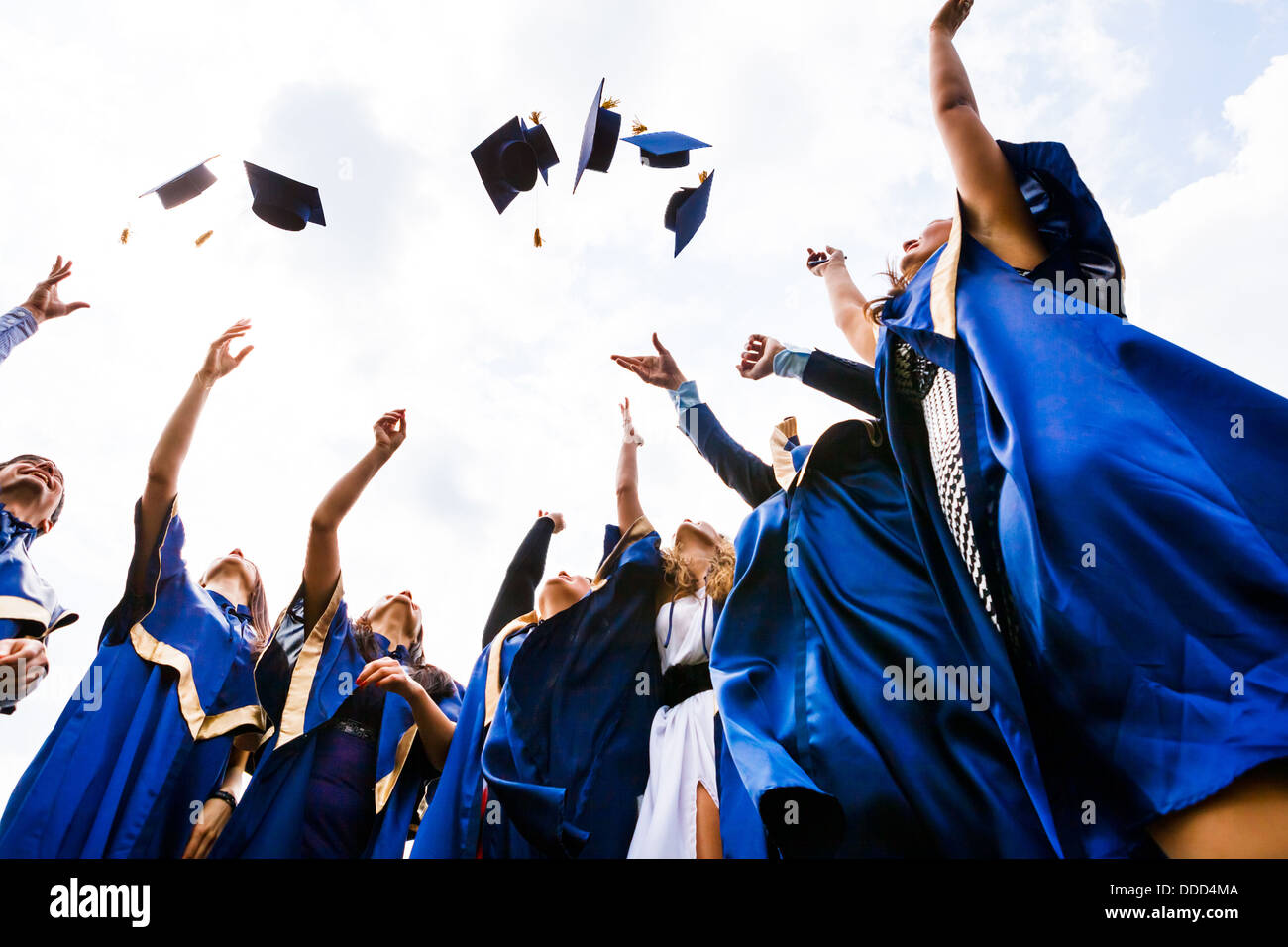 Bild der glückliche junge Absolventen, die Hüte in die Luft werfen Stockfoto