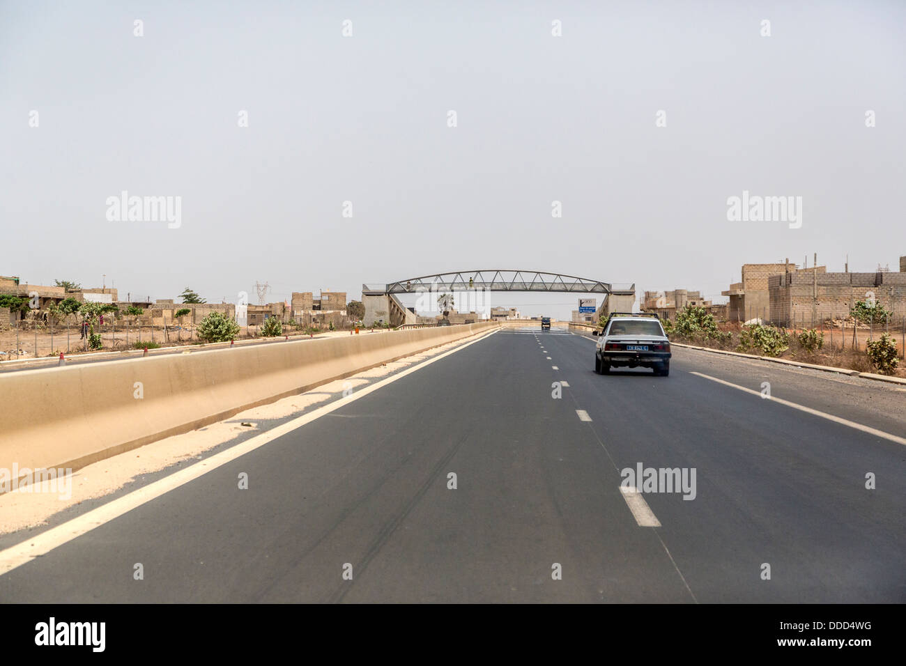 Moderne 4-spurige Divided Highway in der Nähe von Dakar, Senegal. Fußgängerbrücke in Ferne. Stockfoto