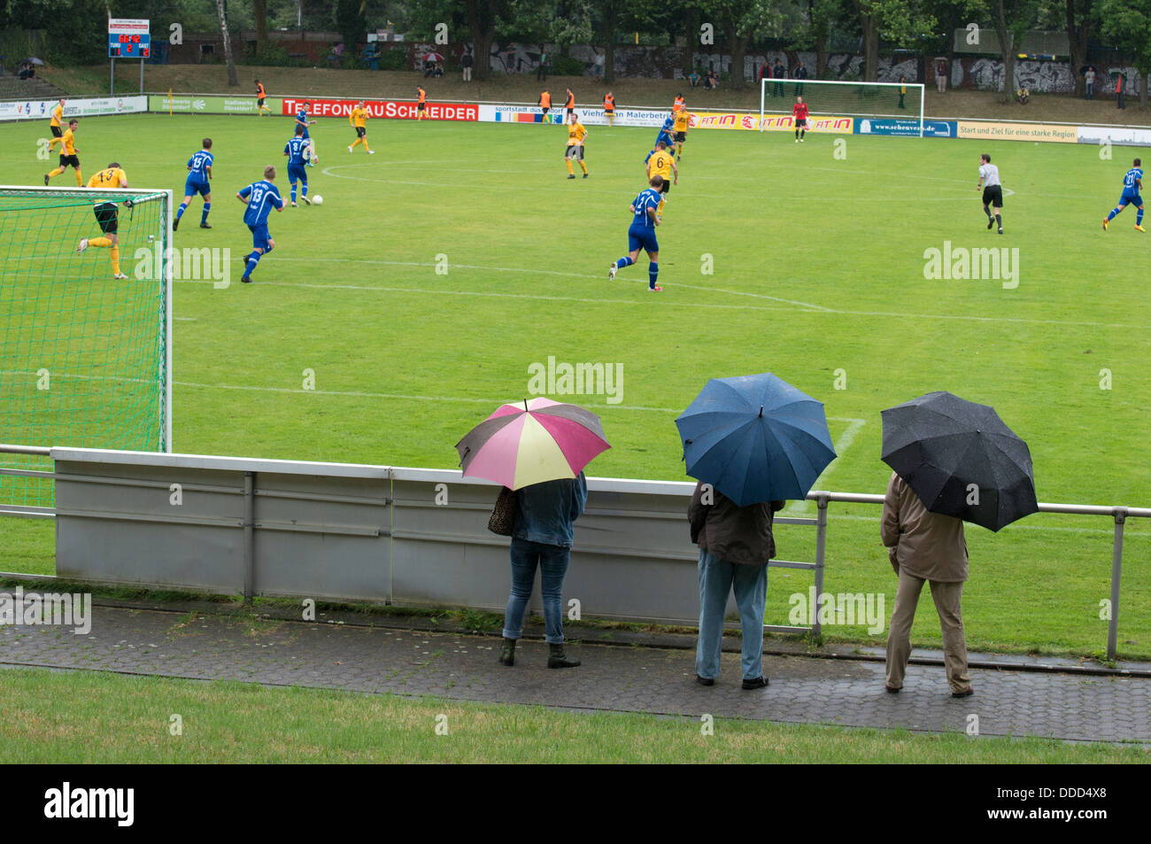 Fans von TuRU 1880 Düsseldorf stehen im Regen gerade ein Spiel gegen SV Honnepel-Niedermormter 18.08.13 (1-2) Stockfoto