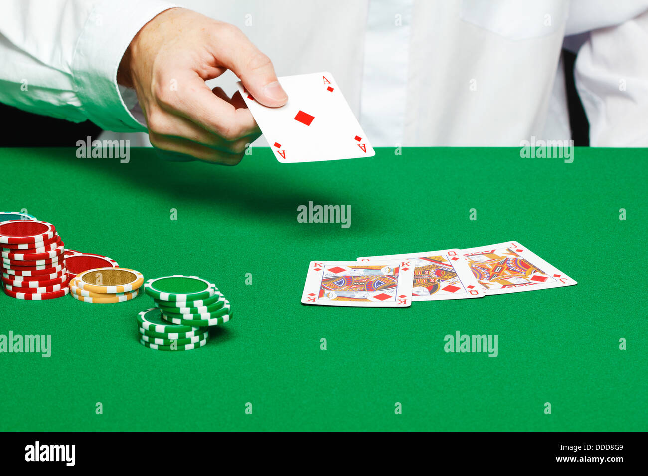 Hand des Spielers wirft eine Spielkarte auf den Tisch Stockfoto