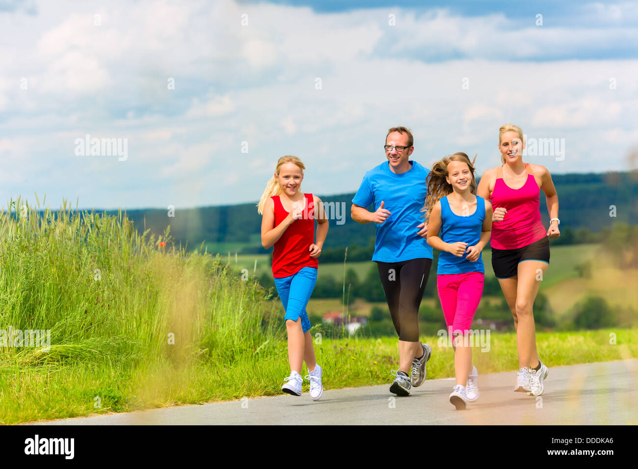 Familie - Mutter, Vater und vier Kinder - jogging oder Outdoor-Sport für Fitness auf ländliche Straße Stockfoto