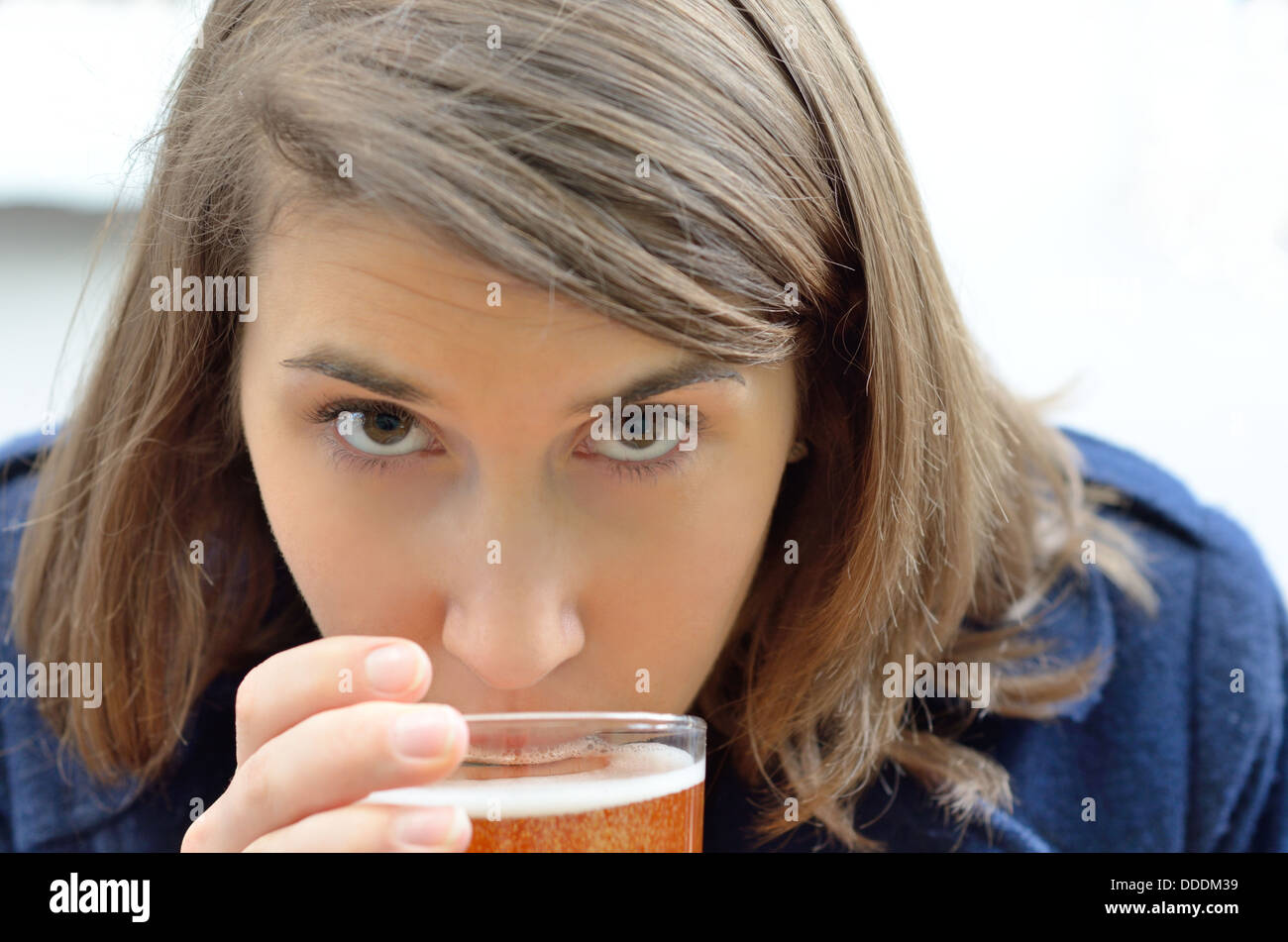 Junge Frau im Mantel, trinken ein Bier in die Kamera schaut Stockfoto