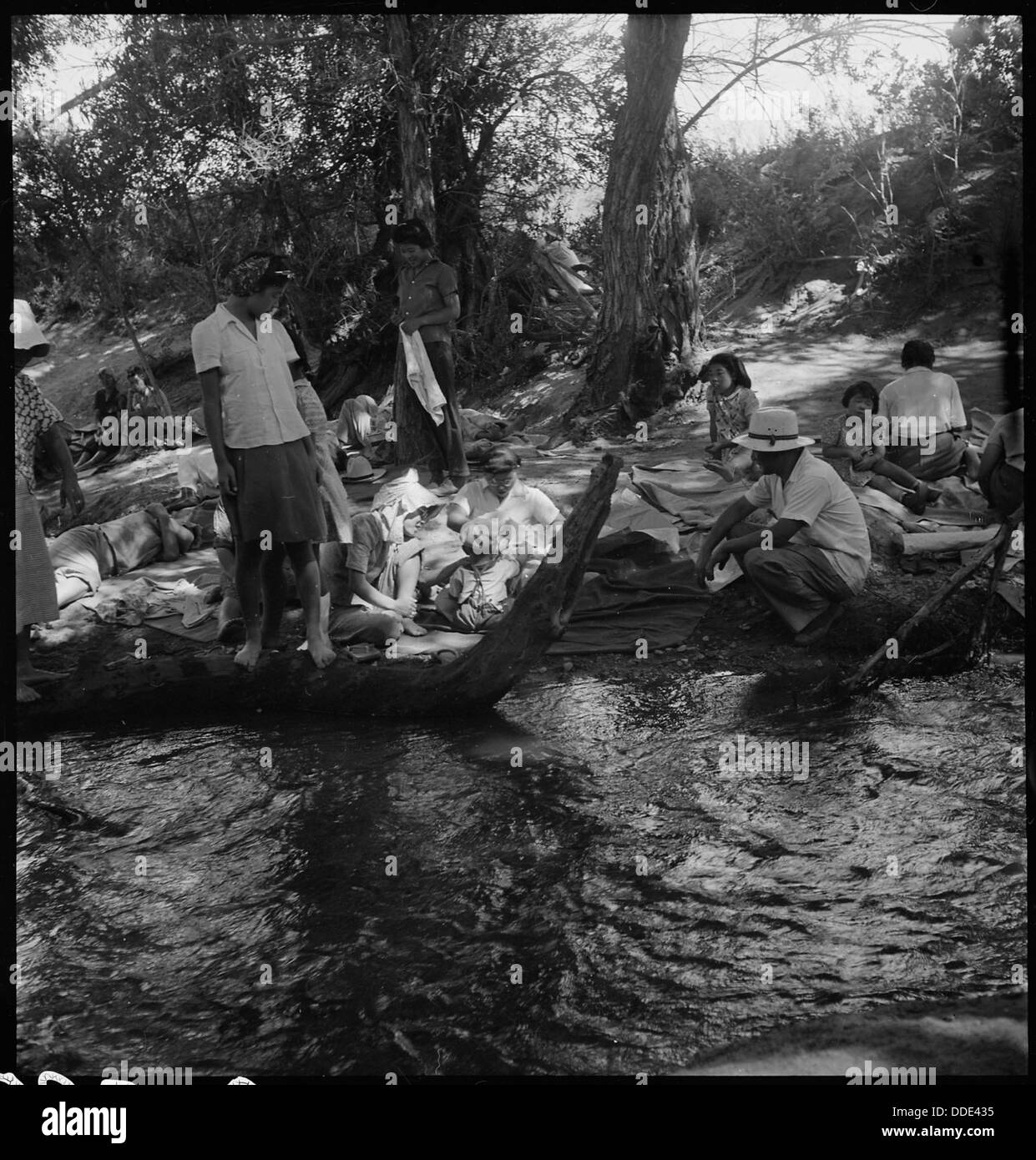 Familiengruppen im Manzanar Relocation Center in Kalifornien genießen einen Bergbach. Dieses Foto zeigt einen Moment des täglichen Lebens im Internierungslager während des Zweiten Weltkriegs und veranschaulicht Familienaktivitäten unter schwierigen Bedingungen. Stockfoto