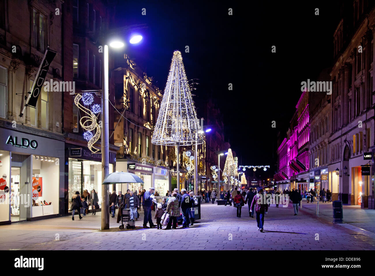 Winterabend, Buchanan Street Glasgow. Shopper & Pendler passieren die Geschäfte und eine Gruppe von Menschen beobachten einen Ballon-Bildhauer Stockfoto