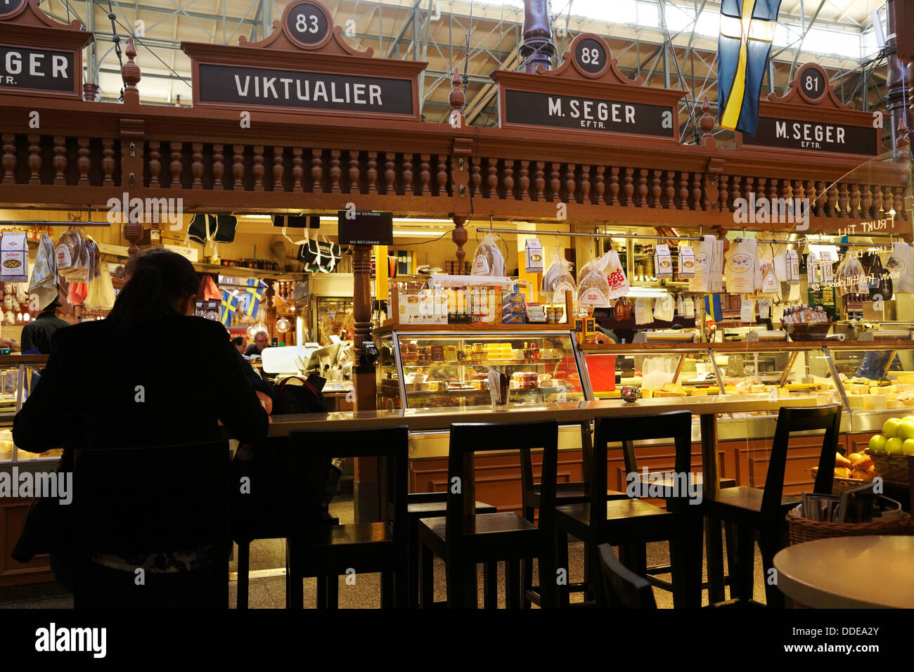 Stockholm, Schweden. Die Ostermalm Saluhall. Mann in der Silhouette, die an einem Tisch essen. M.Seger Essen im Hintergrund. Stockfoto