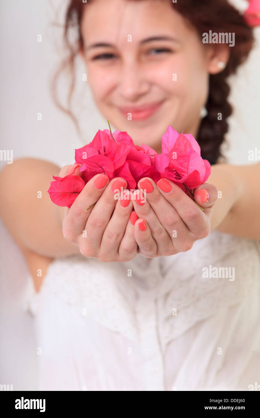 Lächelnde junge Frau, die Blütenblätter in ihren Händen hält Stockfoto