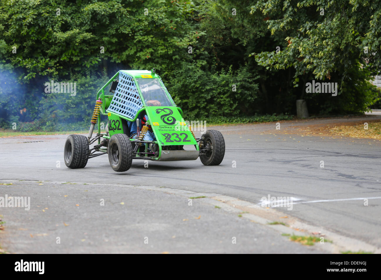 Green Racing Buggy auf Asphalt unter einer Kurve auf 3 Rädern, mit Rauch hinter. Fokussiert auf die Auto Stockfoto