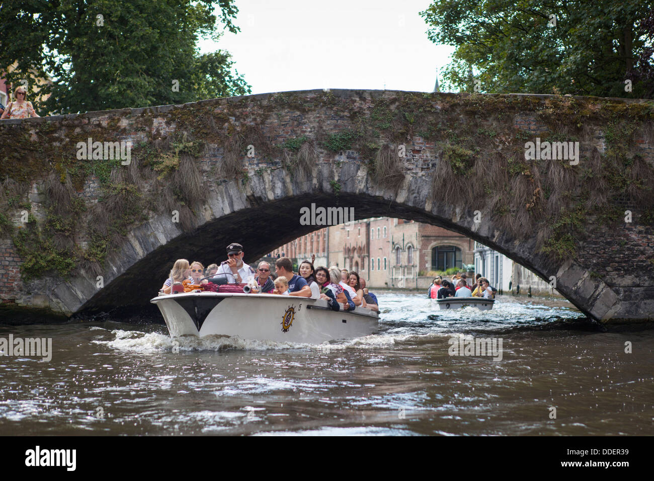 Ausflugsboot in einem der Kanäle in Brügge (Belgien) vorbei an der Blinde Ezelbrug (Blinde Esel Brücke), die älteste Brücke Stockfoto