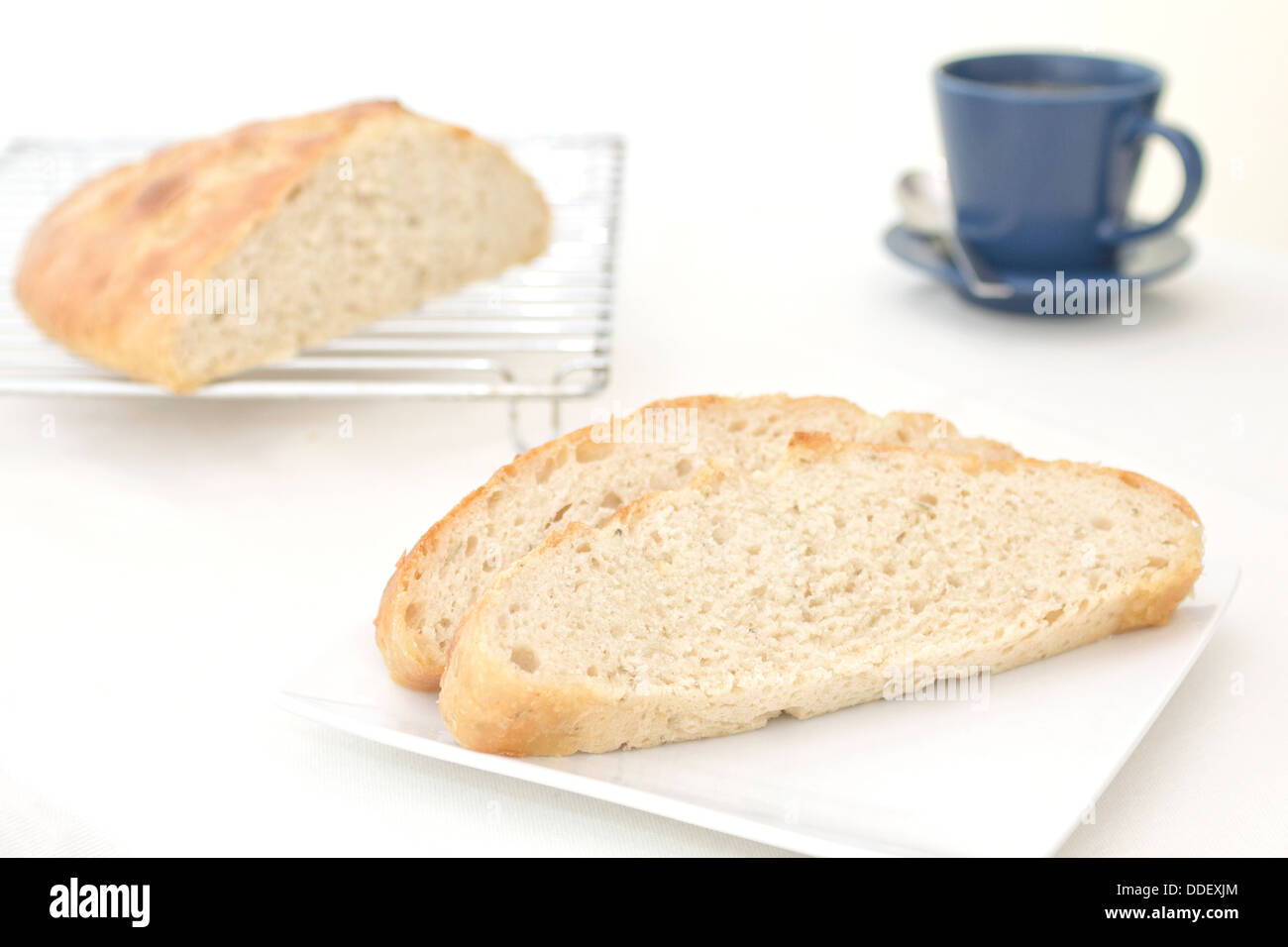 Scheiben Knoblauch und Rosmarin Focaccia Brot auf einem Teller mit den geschnittenen Laib auf ein Kuchengitter im Hintergrund Stockfoto