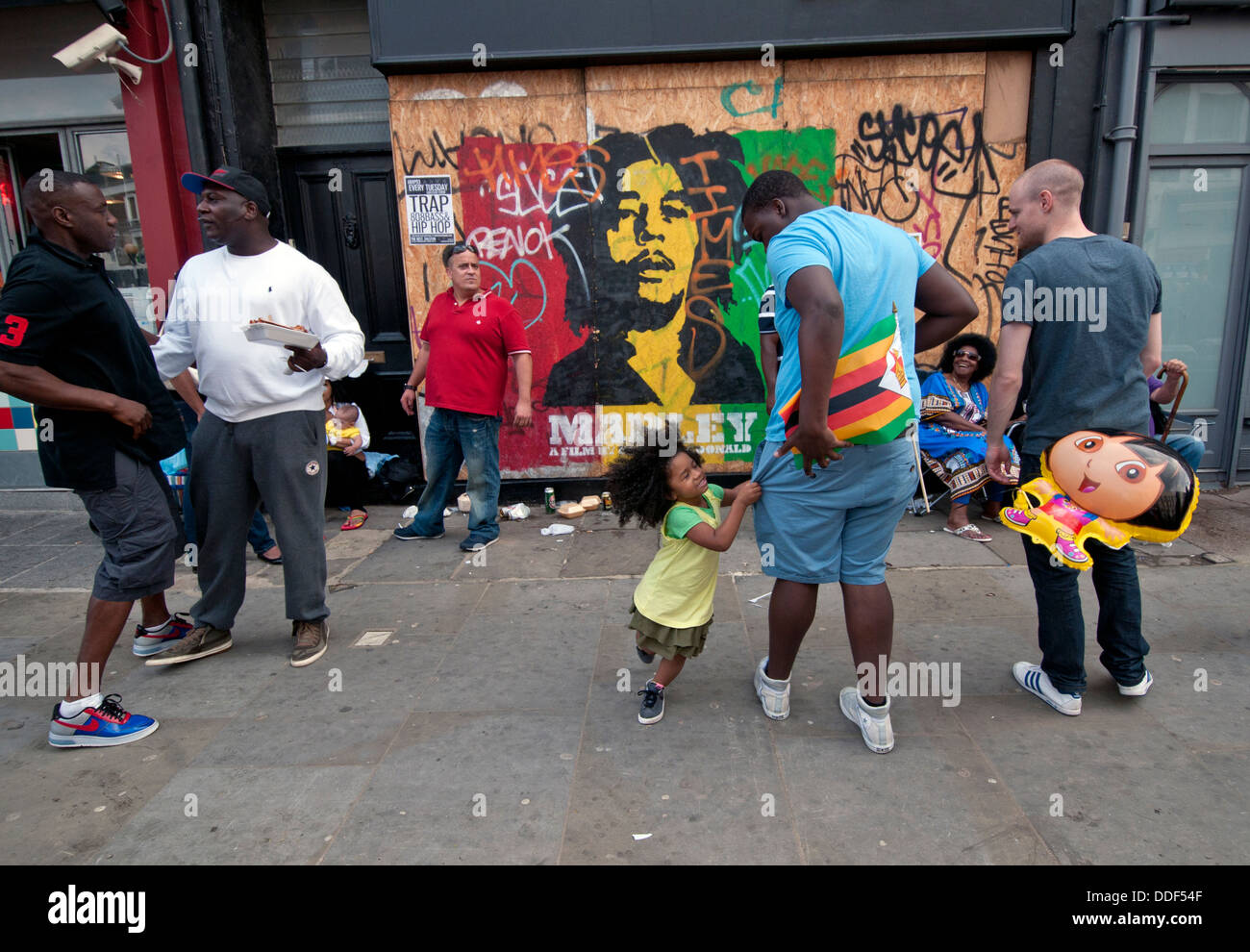 Gruppe von Freunden mit Kindern vor vernagelt Ladenfront im Westen Londons. Stockfoto