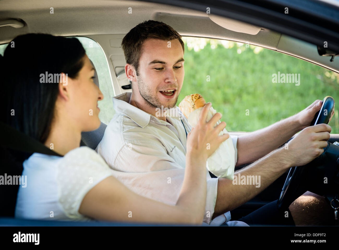 Paar im Auto - Mann treibt und Frau füttert ihn Stockfoto