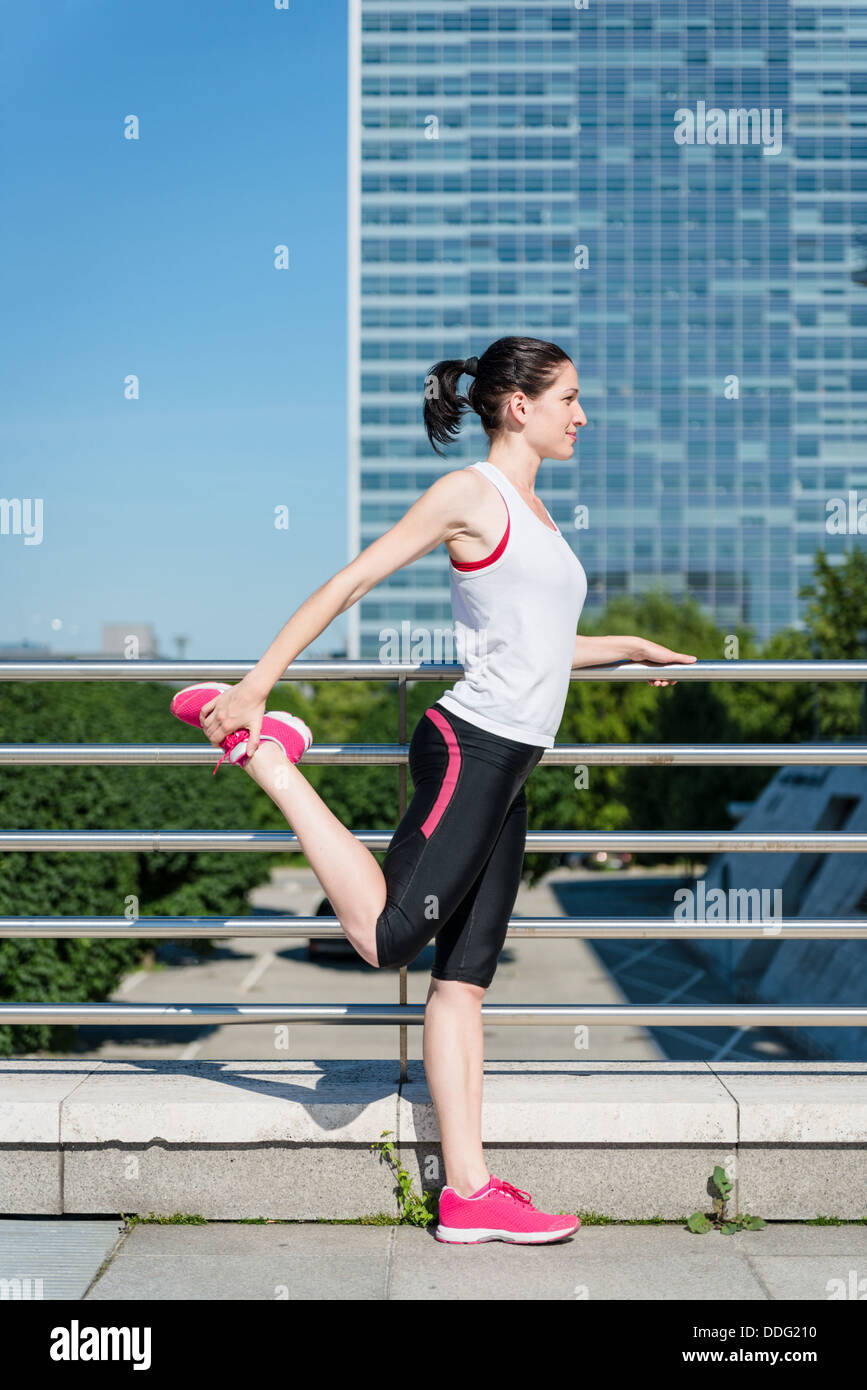 Junge Sportlerin ist Dehnung Bein vor dem Joggen - im Freien in Stadt Stockfoto