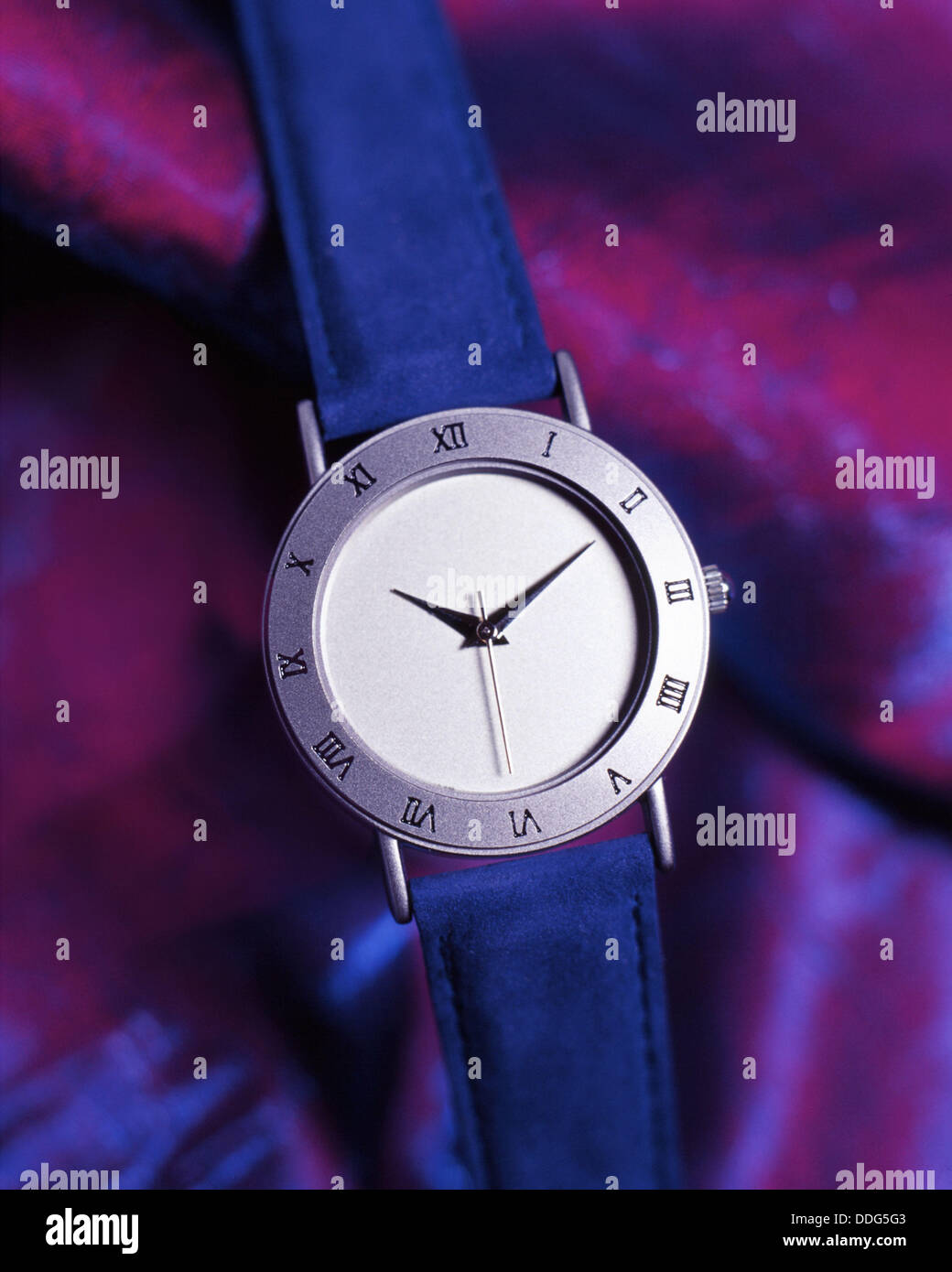 Uhr mit römischen Ziffern auf einem seidenen lila Hintergrund Stockfoto