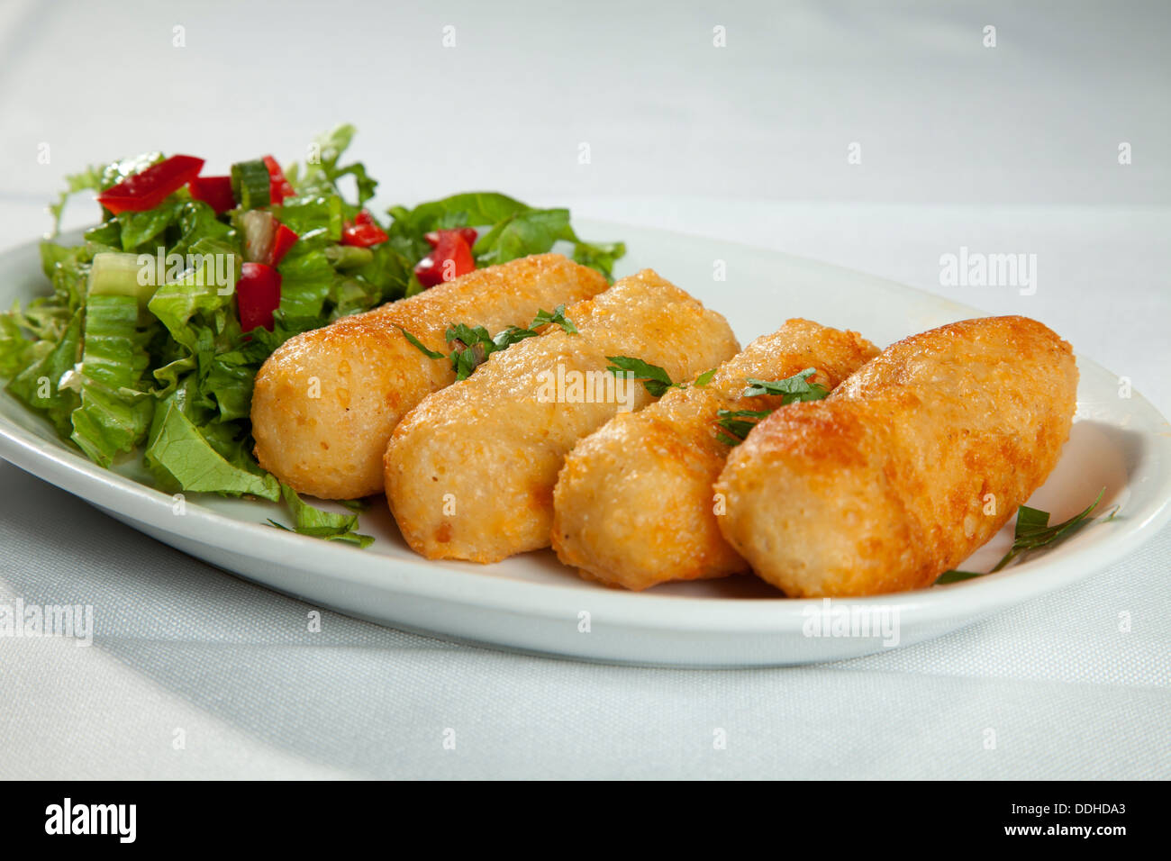 Vier Kase Kroketten Mit Grunem Gemuse Salat Serviert Geschnitten Tred Pfeffer Auf Weissem Ton Die Sich Auf Der Weissen Tischdecke Auf Dem Tisch Stockfotografie Alamy