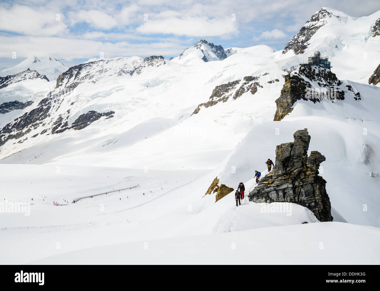 Kletterer auf dem Jungfraujoch mit Sphinx-Observatorium hinter. Die oben genannten Rottalhorn und Finsteraarhorn in Wolke auf der linken Seite Stockfoto