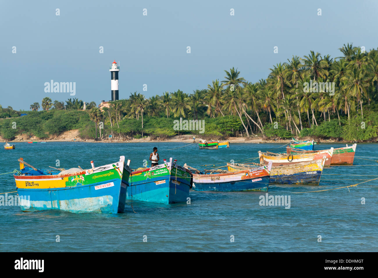 Bunte Fischerboote und Palmen, Leuchtturm am Rücken Stockfoto