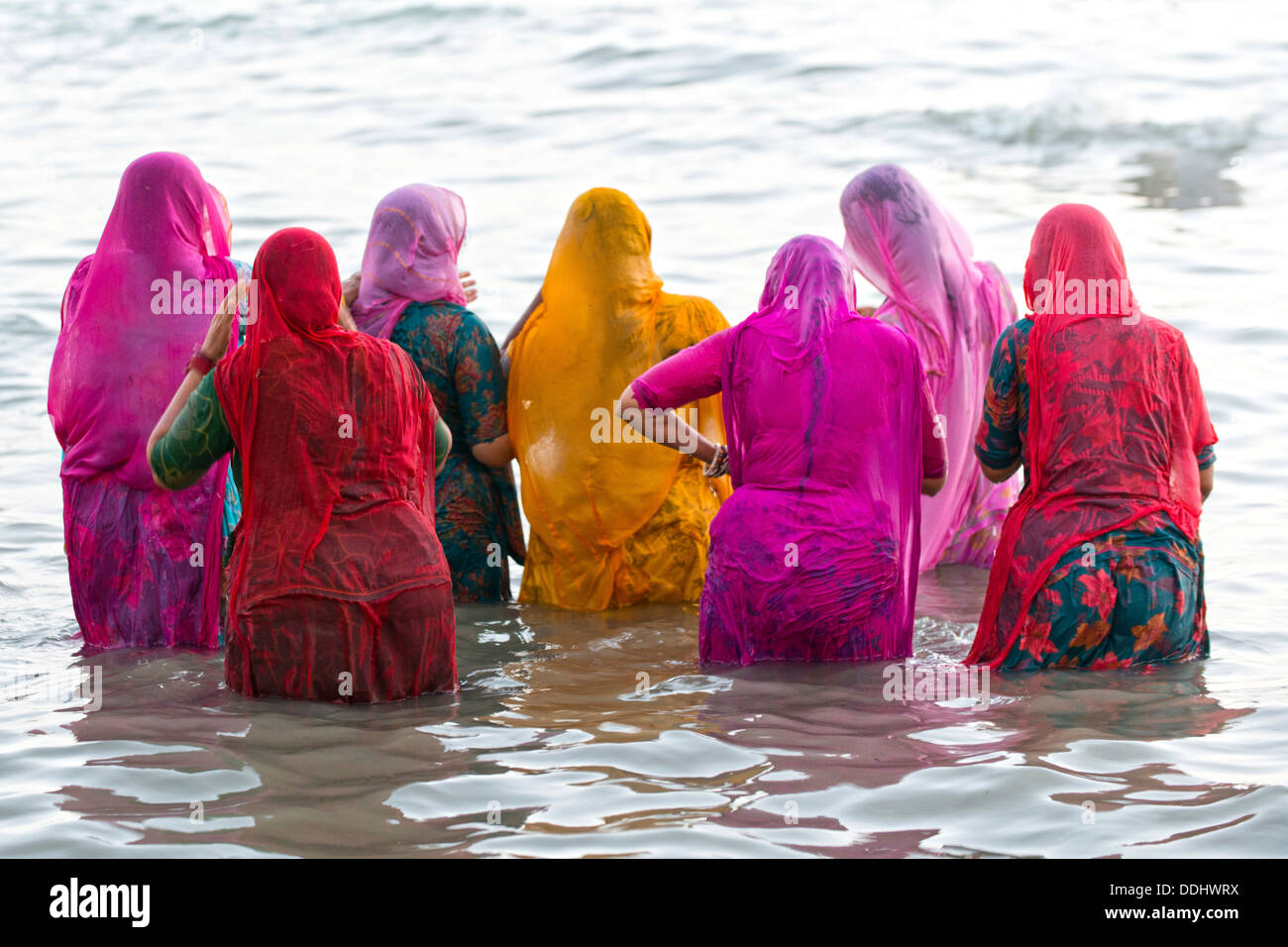 Hindu-Pilger Baden Frauen in bunten Saris, die unter einem Heiligen Om Meer vor Sonnenaufgang am Ghat Agni Theertham Stockfoto