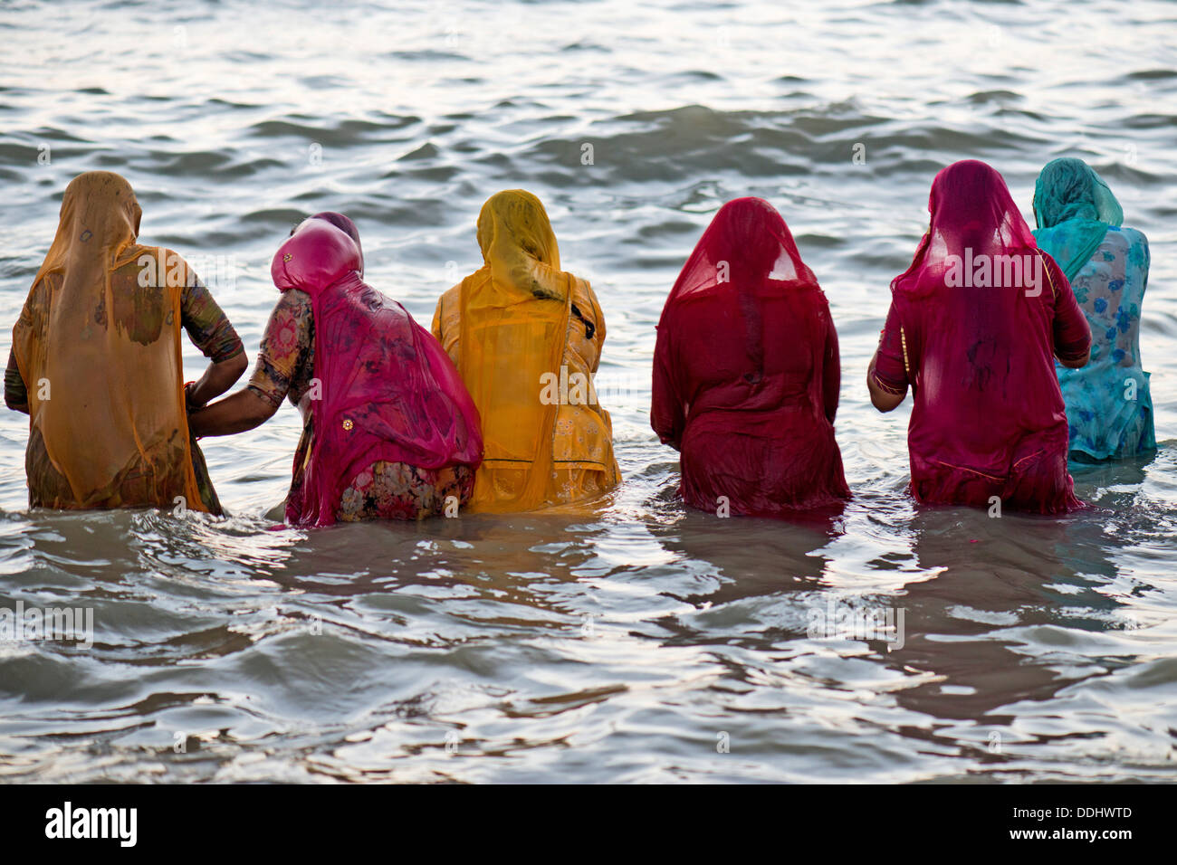 Hindu-Pilger Baden Frauen in bunten Saris, die unter einem Heiligen Om Meer vor Sonnenaufgang am Ghat Agni Theertham Stockfoto