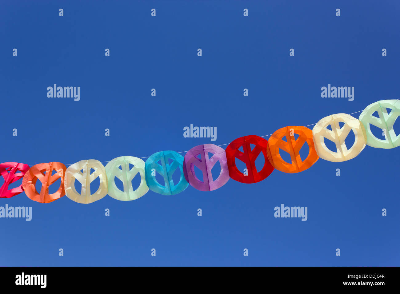 Papier Girlande aus bunten Peace-Zeichen gegen blauen Himmel. Stockfoto