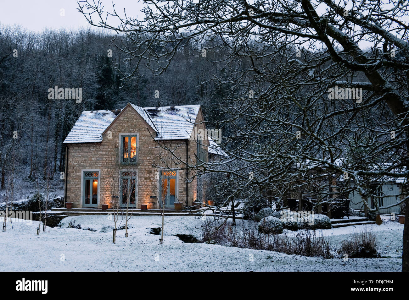 Winterliche Außenfassade des Keepers Cottage aus dem Garten und über den Bach zu sehen Stockfoto