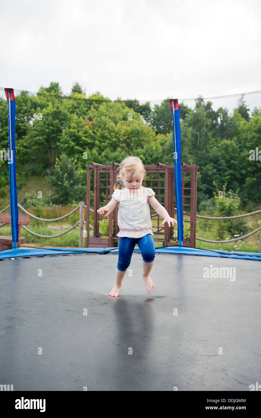 kleine Mädchen spielen auf einem Gartentrampolin Stockfoto