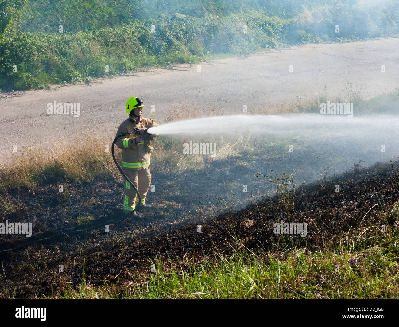 Feuerwehrmann Aufguss eine Rasen-Feuer, Kent, UK, Sommer Stockfoto