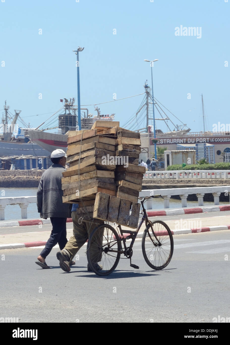 Zwei Männer schieben Holzpaletten auf einem Fahrrad auf einem Weg Stockfoto