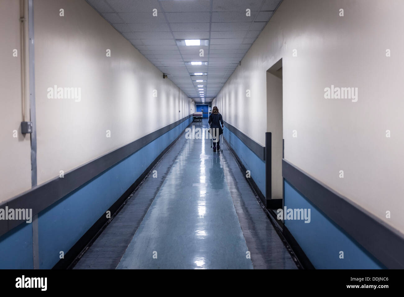 Eine Frau zu Fuß auf Krücken nach unten eine leere Krankenhausflur, NHS, UK Stockfoto