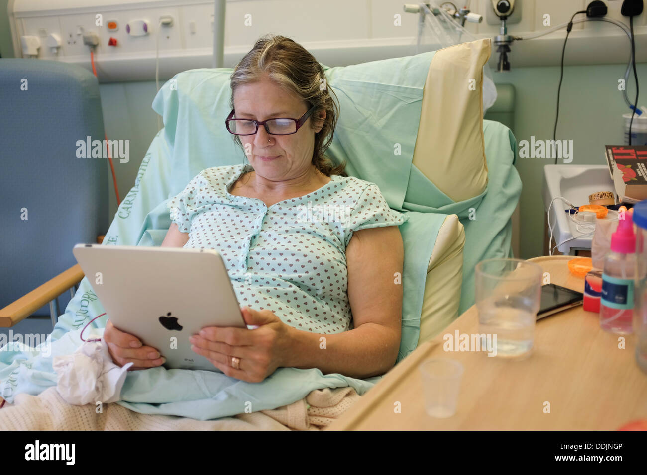 Eine im mittleren Alter Frau liest ihr iPad wiederherstellen im NHS Krankenhaus nach einer Hüft-Ersatz-Operation UK Stockfoto