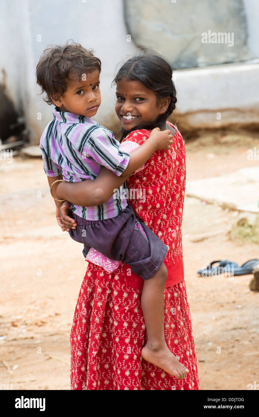 Lächelt glücklich ländlichen Indianerdorf Mädchen trägt ihren Bruder. Andhra Pradesh, Indien Stockfoto