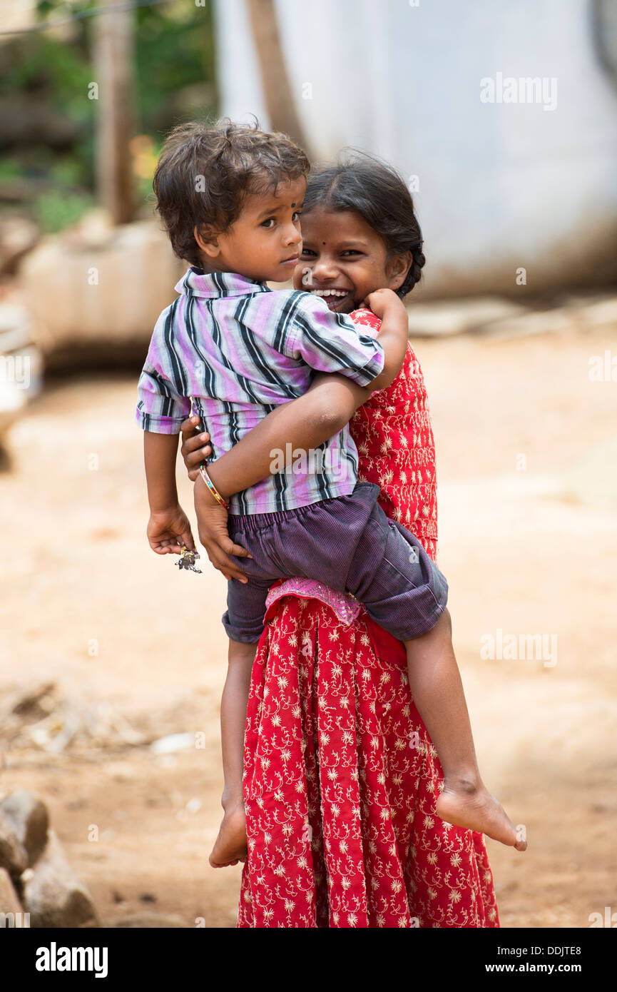 Lächelt glücklich ländlichen Indianerdorf Mädchen trägt ihren Bruder. Andhra Pradesh, Indien Stockfoto