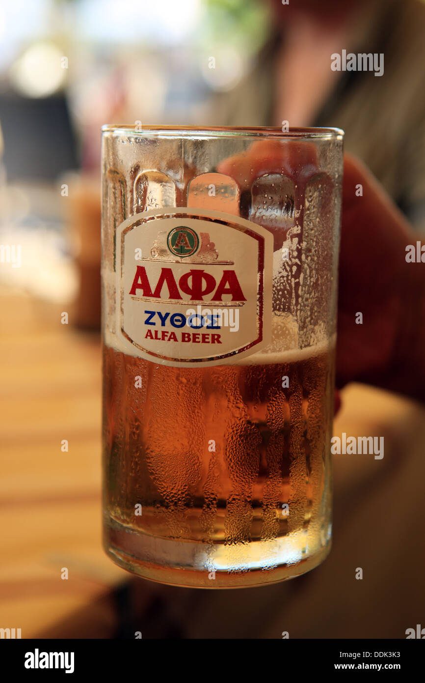 Hand hält ein Glas Alfa Bier in Griechenland Stockfoto