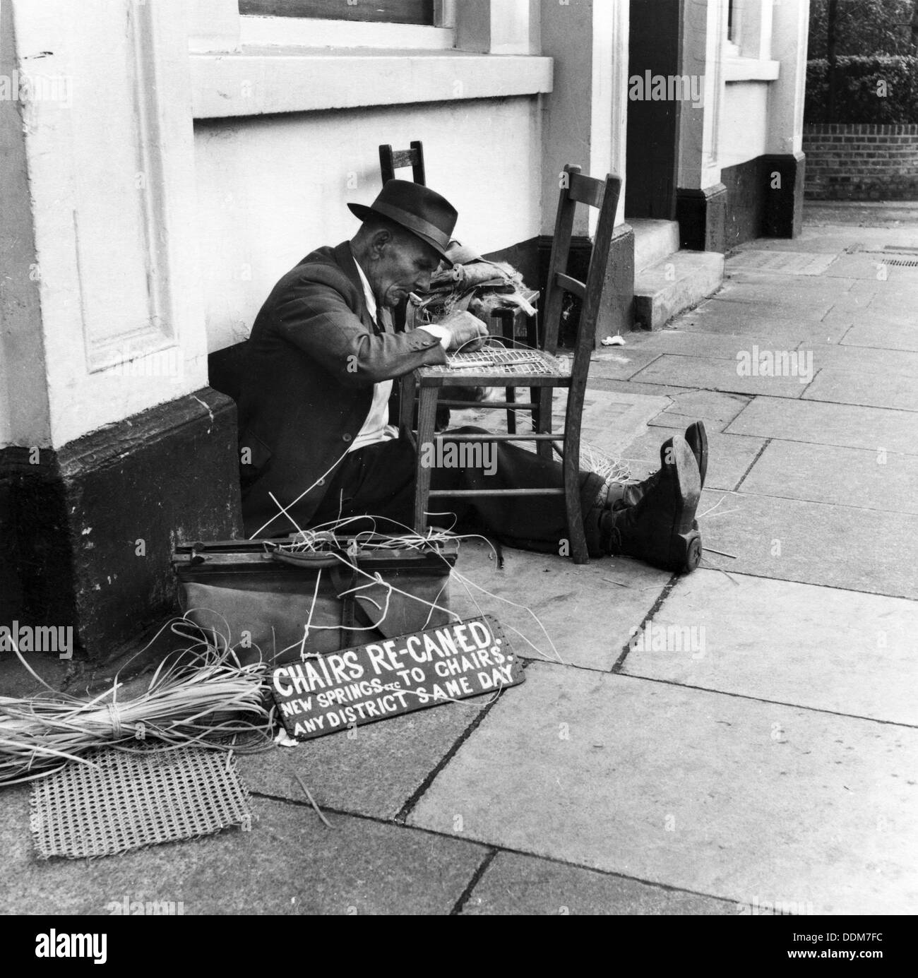 Mann, Ausbessern von einem Stuhl auf eine East End Street, London, 1950er Jahre. Künstler: Henry Grant Stockfoto