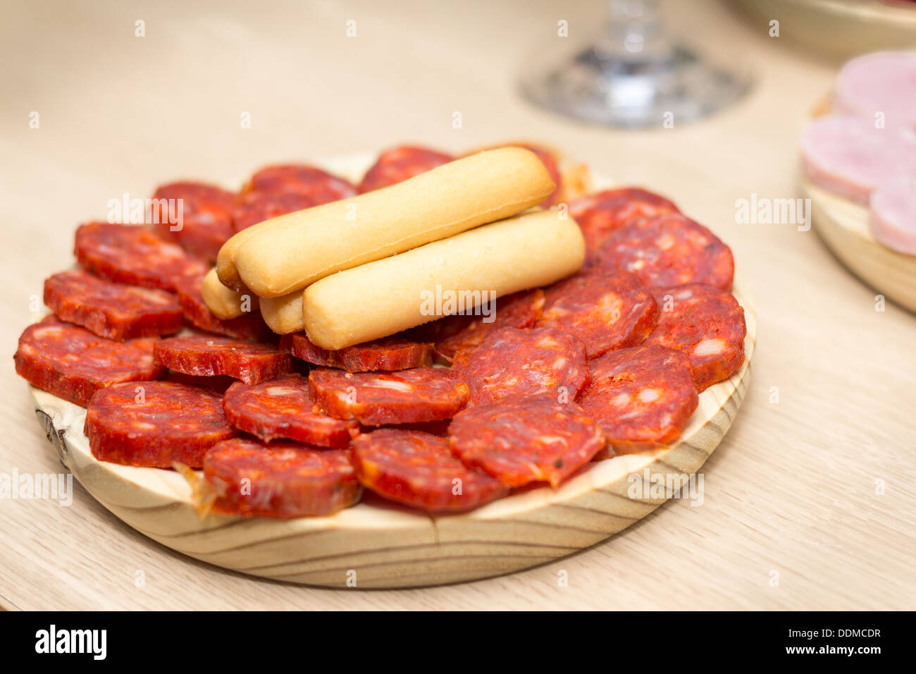 Spanische Chorizo in Scheiben geschnitten auf einem Holzbrett mit Grissini an der Spitze Stockfoto