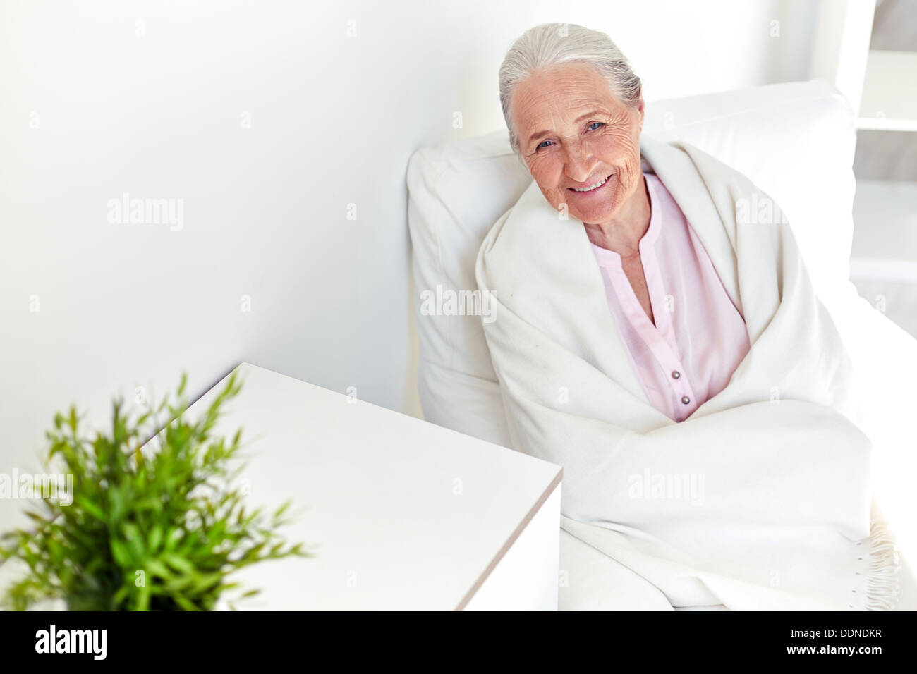 Porträt der älteren Frau im Sessel sitzen und Blick in die Kamera Stockfoto