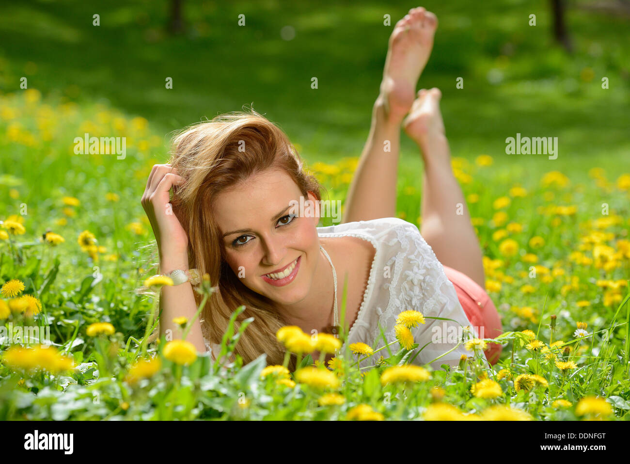 Junge Frau liegt auf einem Löwenzahn Wiese im Frühjahr, Porträt Stockfoto