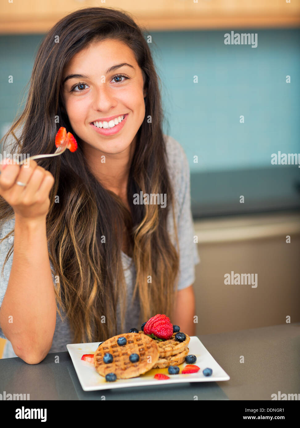 Junge Frau essen Waffeln mit frischen Früchten, Frühstück zu Hause Stockfoto