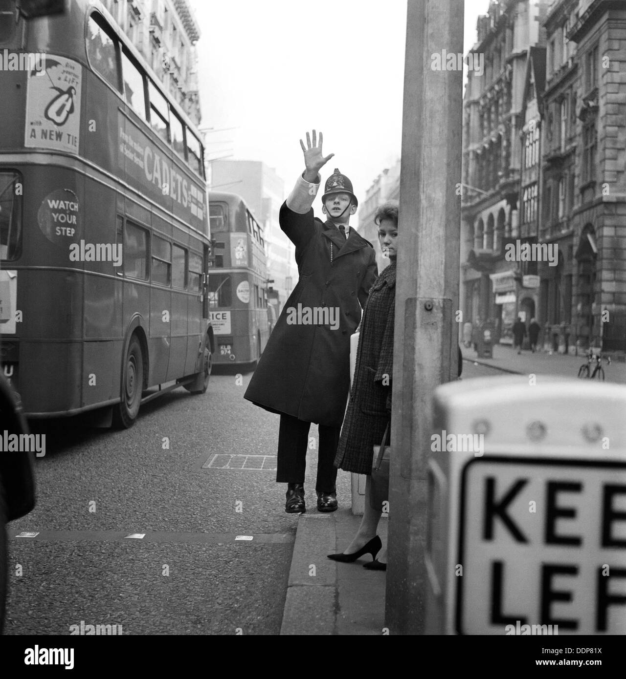 Ein Polizist mit seinem Arm angehoben als 2 Doppeldecker-Busse-Pass durch die City of London c1946-c1959. Künstler: John Gay Stockfoto