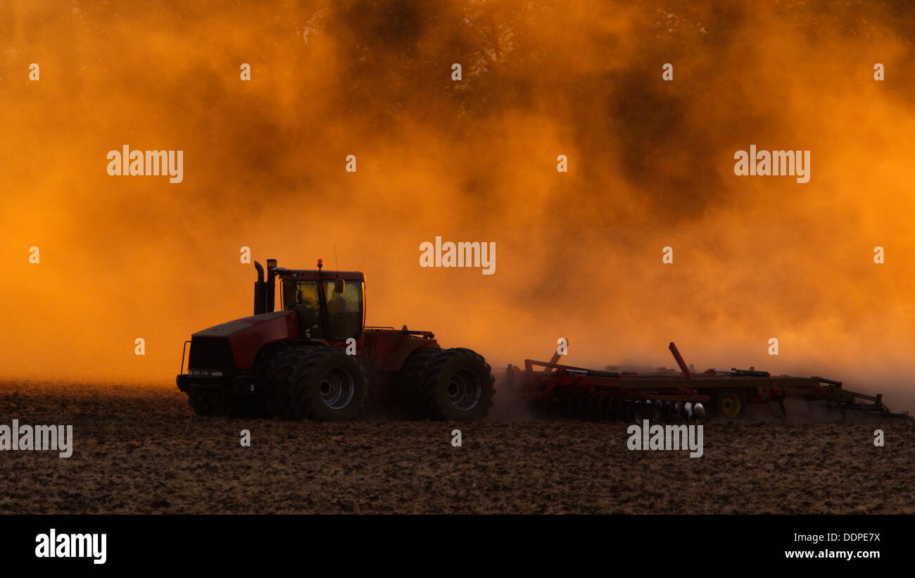 Traktor Pflügen Feld bei Sonnenuntergang Stockfoto