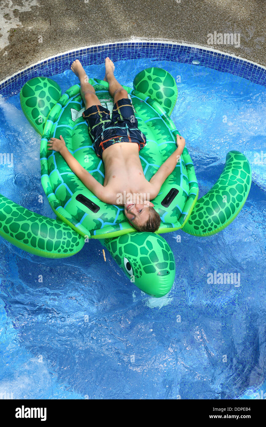 Kleiner Junge Handauflegen aufblasbare Schildkröte im pool Stockfoto