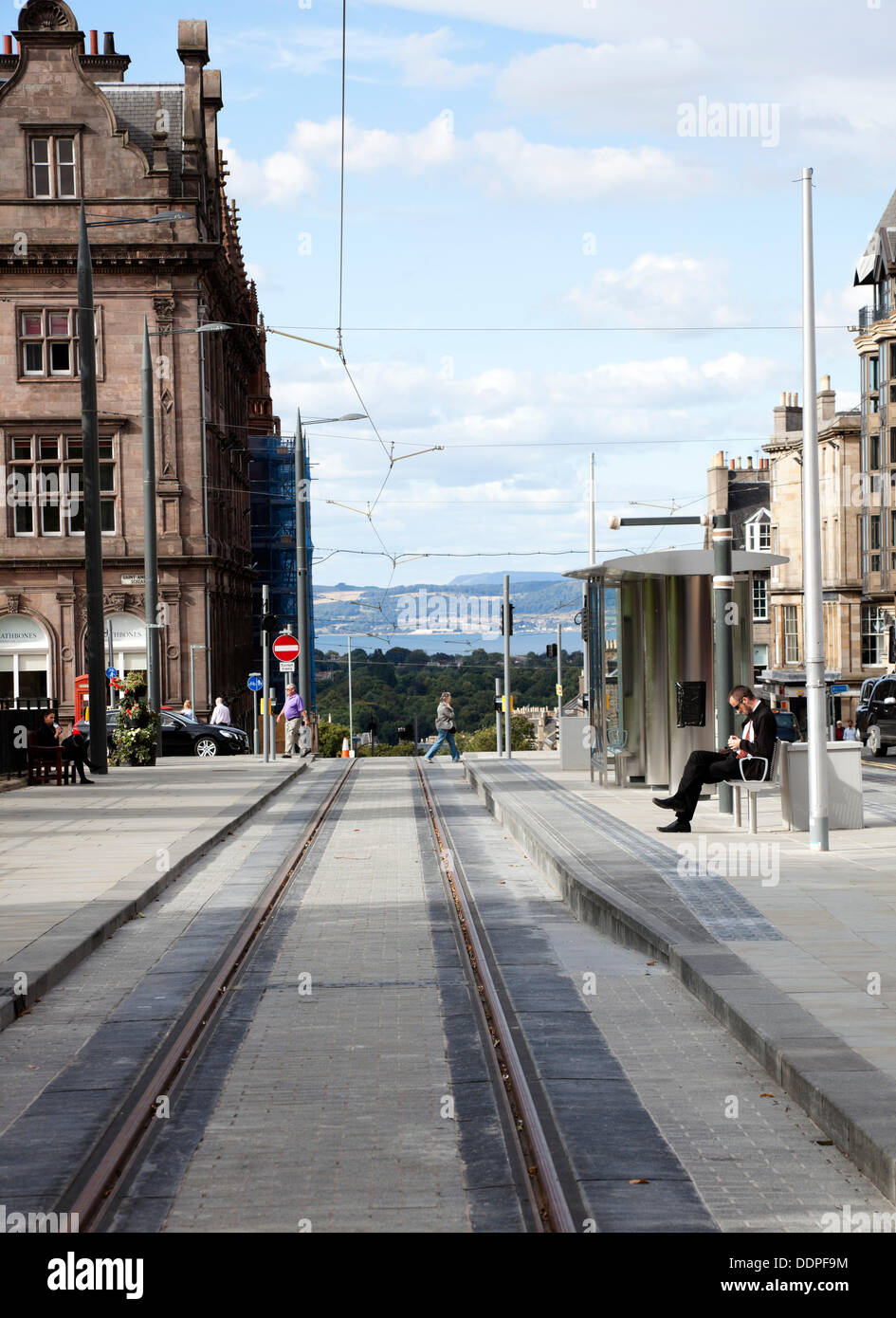 Mann sitzt an Str. Andrews Square Edinburgh Straßenbahnhaltestelle, verzögerte Projekt soll und läuft bis zum Sommer 2014. Stockfoto
