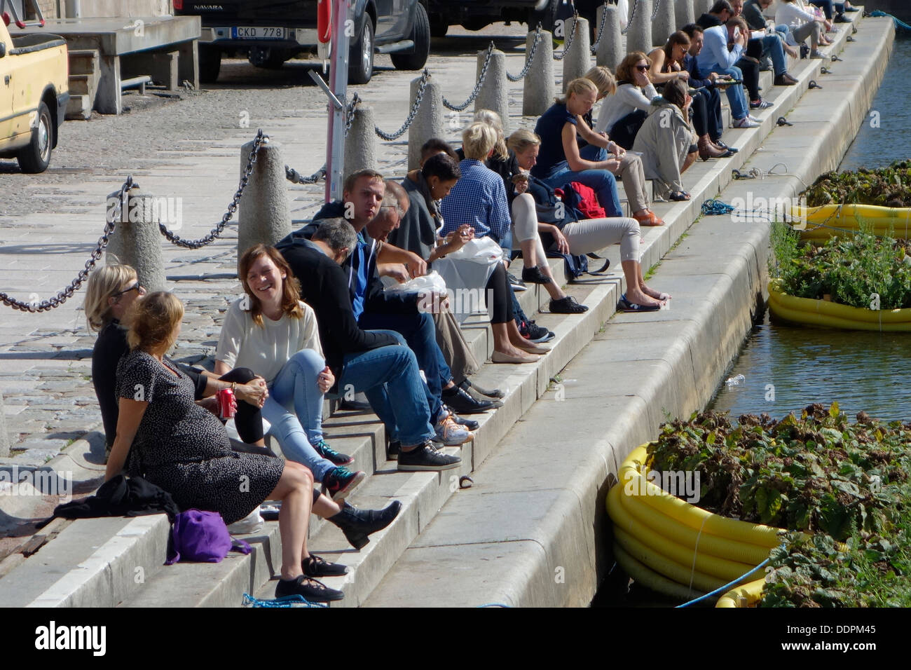 Stadt-Bewohner Menschen entspannen am Fluss Kai an einem normalen Werktag während der Mittagszeit. Rosenlund, Göteborg, Schweden Stockfoto