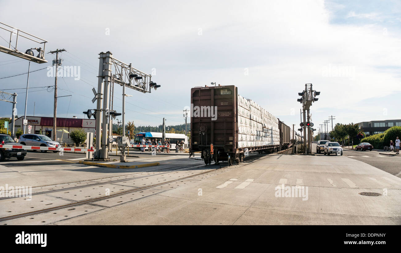Heckansicht des langen Güterzug bewegen durch & abseits Bahnübergang warten Autos & Fußgänger in Edmonds, Washington Stockfoto