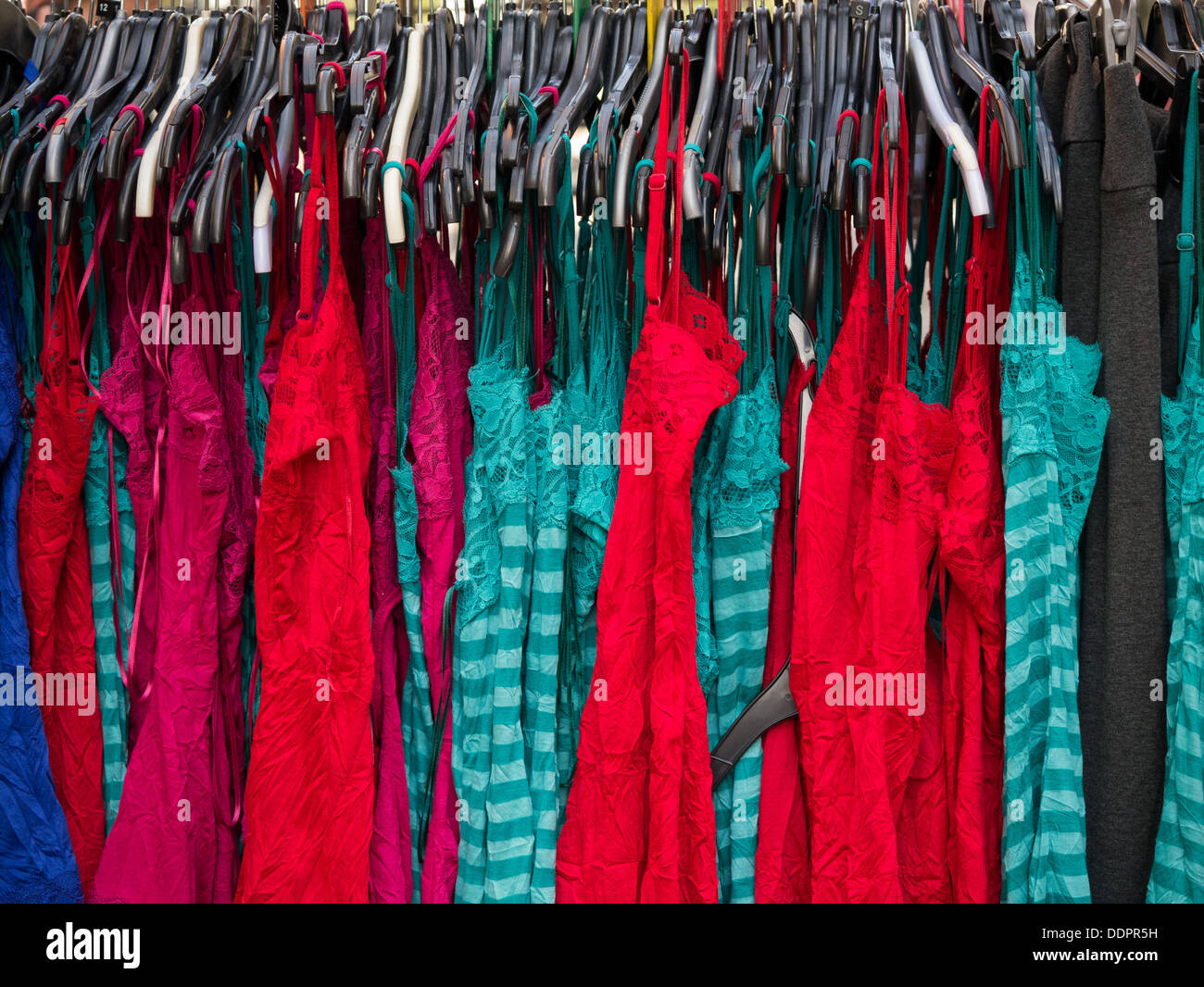 Bunte Kleider hängen im Petticoat Lane Straßenmarkt in London Stockfoto