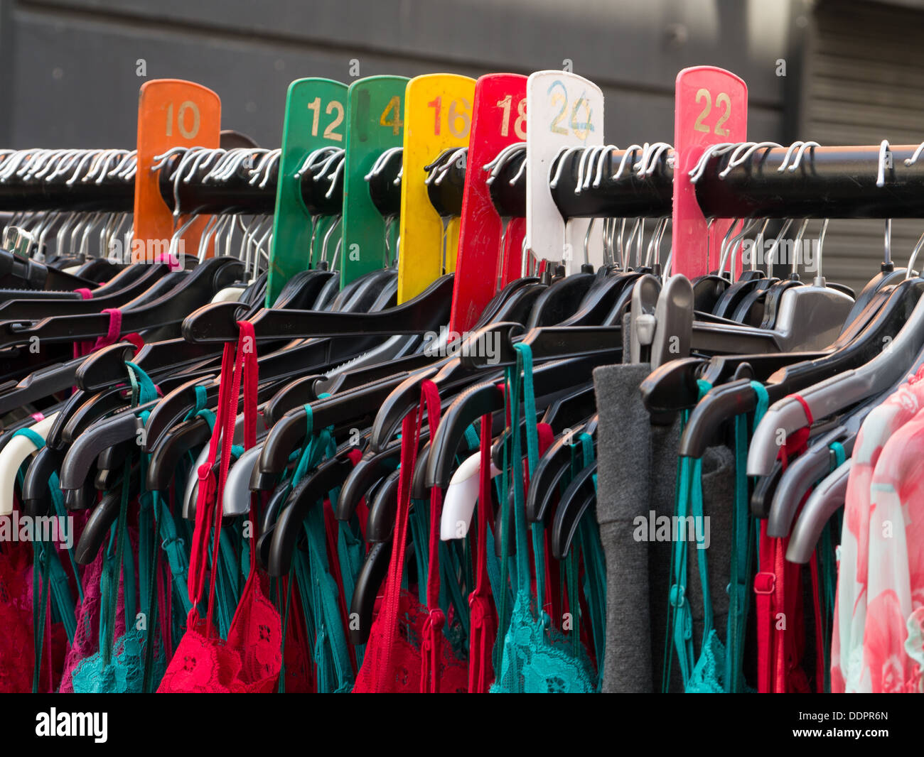 Bunte Kleider hängen im Petticoat Lane Straßenmarkt in London Stockfoto