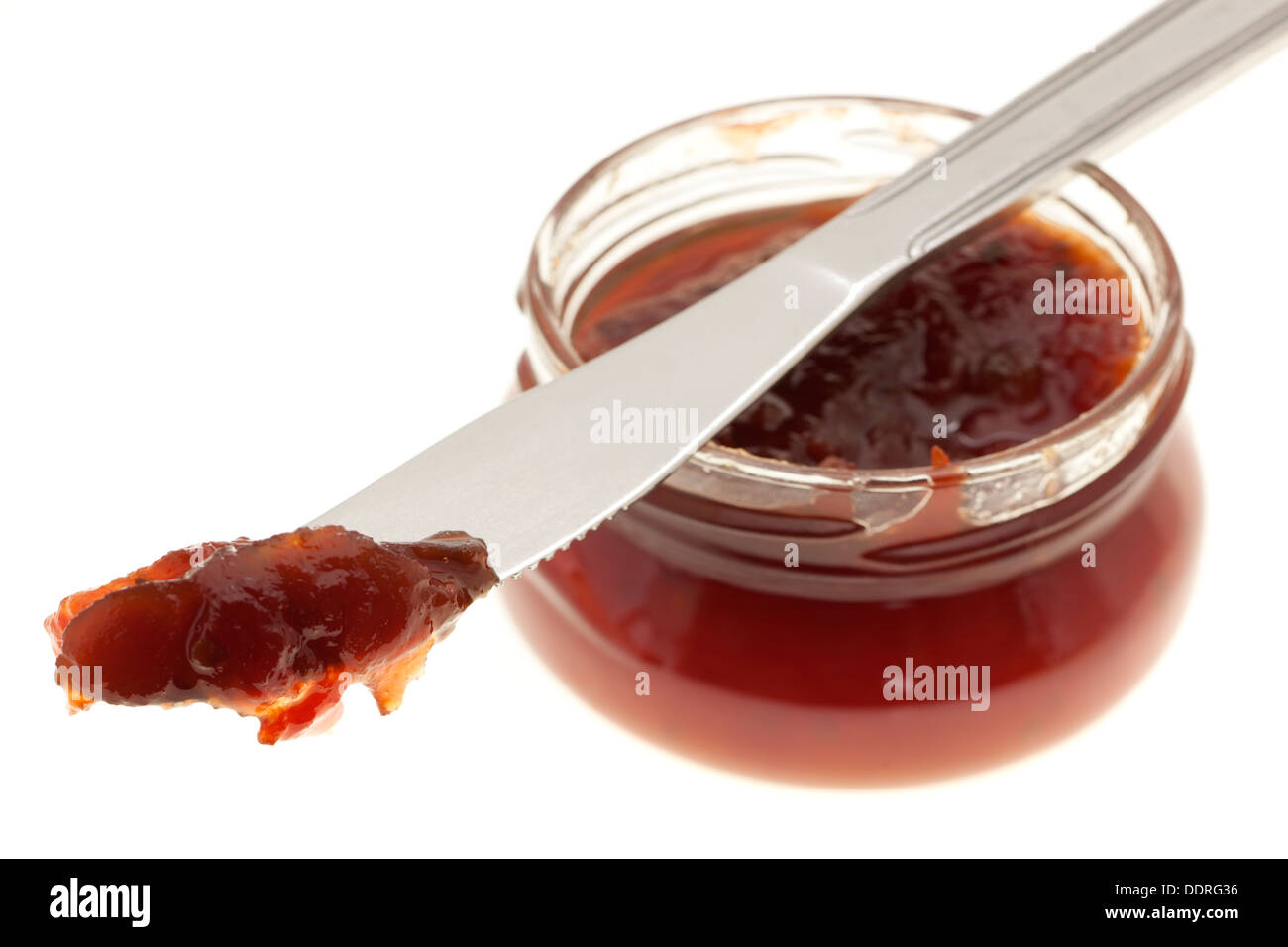 Portion Tomatenmarmelade auf ein Messer und Glas Stockfoto