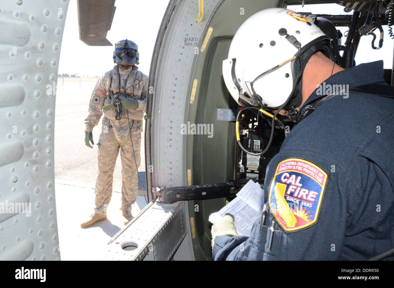 Bereiten Sie CAL Fire Manager, Feuer Capt John Zungea, rechts, der US Forest Service Feuerwehrleute auf dem Boden und Signale Spc. Michael Beatty, ein UH-60 Black Hawk Crewchief von 1-140. Aviation Battalion (Air Assault), Sitz in Los Alamitos, Flecken Stockfoto