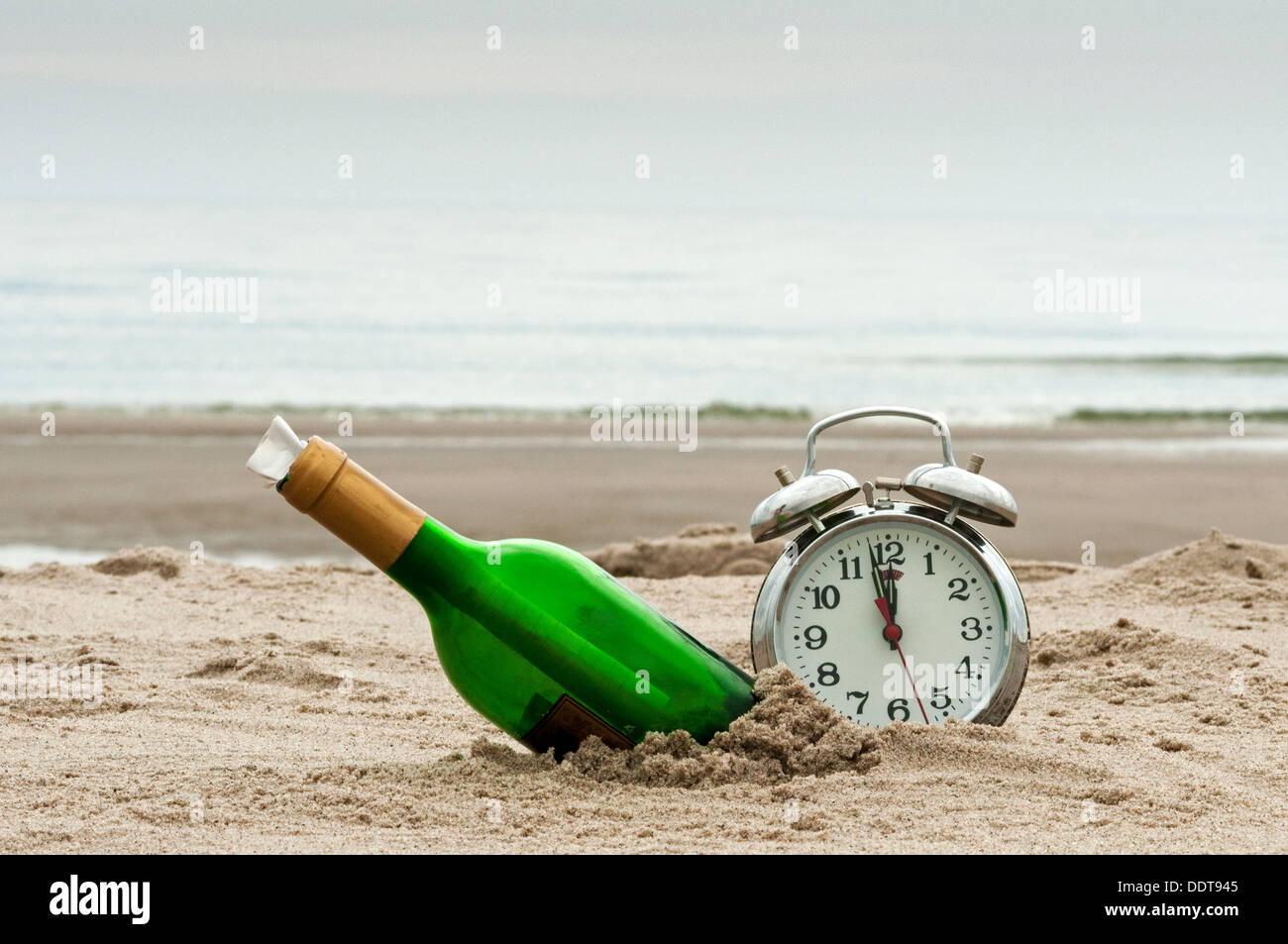 Flaschenpost am Strand mit Wecker Stockfoto