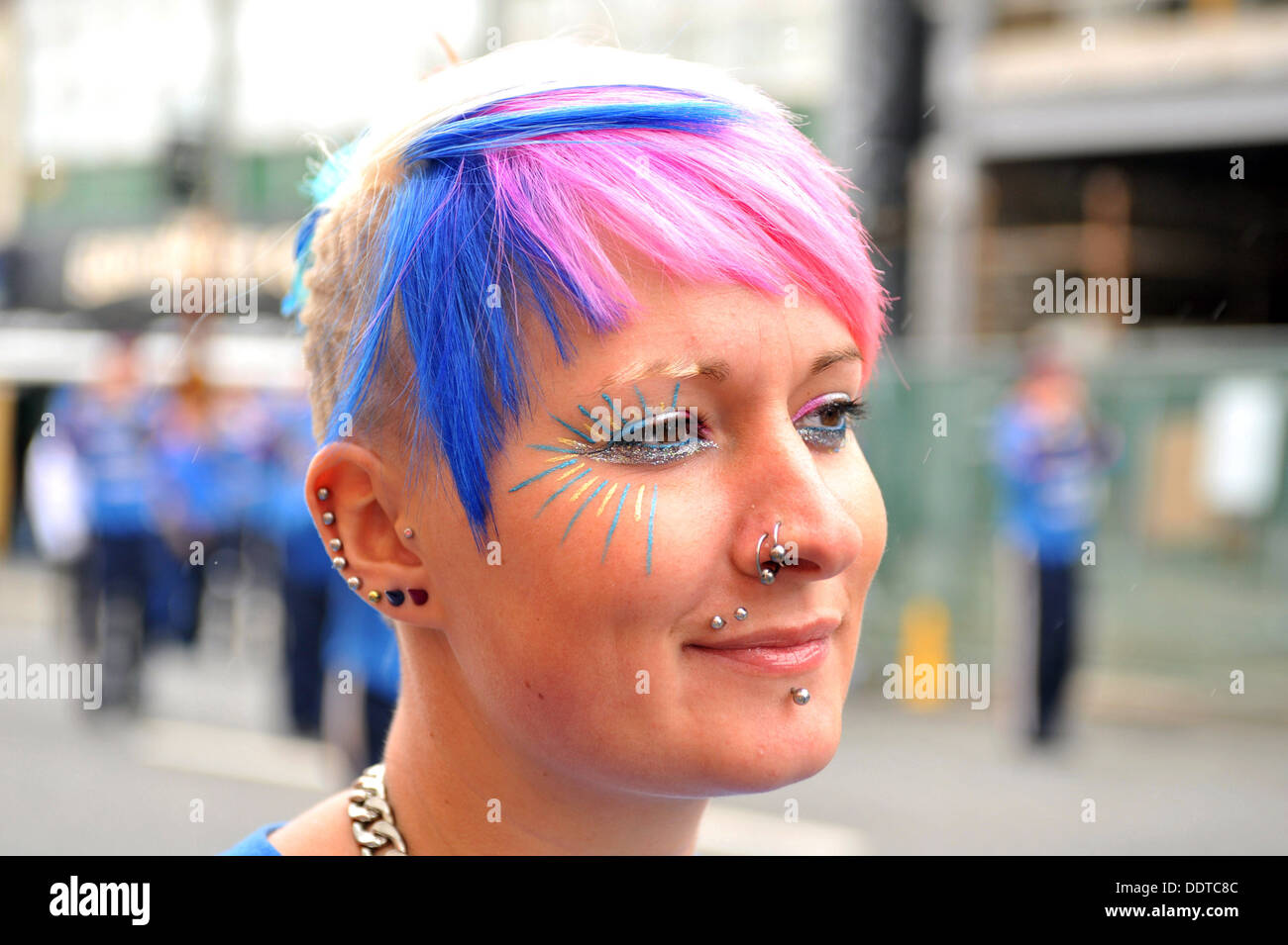 Eine junge Frau hat Haare gefärbt rot, weiß und blau mit Piercings. Stockfoto